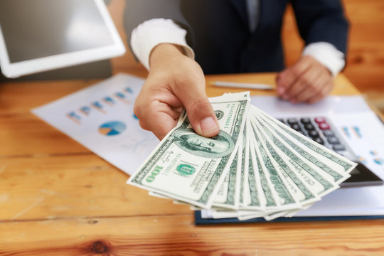 Man offering batch of hundred dollar bills. Man Displaying a Spread of Cash.