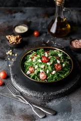 Foto op Plexiglas Healthy vegetable salad with fresh arugula, tomato, feta cheese and walnut on dark plate. Diet menu. Top view. Salad with arugula  © Agnes
