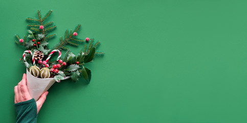 Christmas panoramic background flat lay on green paper with copy-space. Female hand holding veneer...
