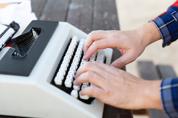 Manos de persona tecleando en maquina de escribir vintage en mesa de madera.