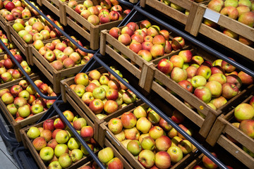 Diagonal view of wooden lug boxes with ripe apples on counter in supermarket