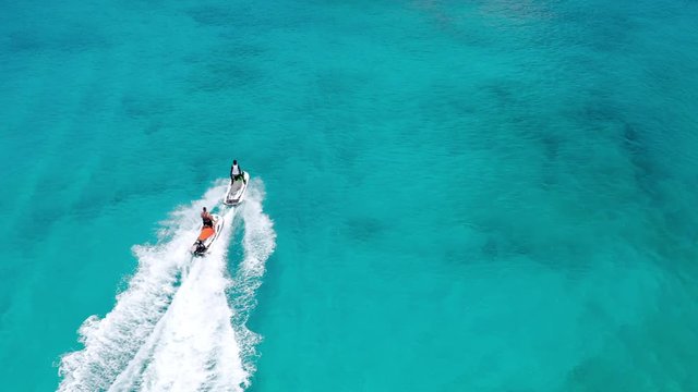 Aerial: Two People Jet Skiing in Crystal Clear Blue Water Leaving Foamy Wake Behind - Nassau, Bahamas