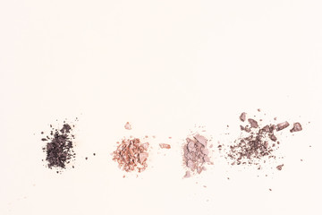 Scattered eyeshadows of beige and brown shades on a light background. The concept of decorative cosmetics, makeup. Minimalism. Copy space.