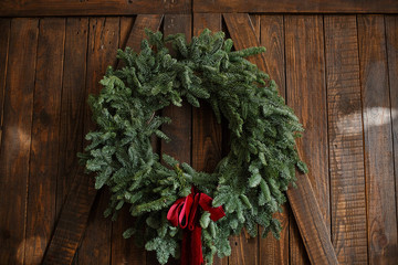 Christmas decorations. A wreath of spruce branches with cones on dark wooden background. Selective focus
