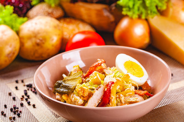 Potato salad with chicken and bacon in beige bowl