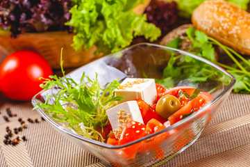 Salad with tomatoes, herbs and cheese in glass bowl