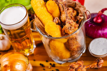 Fototapeta na wymiar Fish fingers and fried chicken in glass bowl served with beer