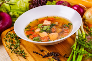 Soup with salmon, vegetables and spices in white plate