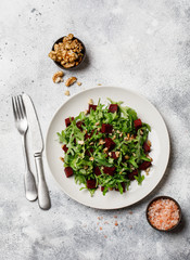Fresh salad with arugula, feta cheese, walnut and beet on white plate. Beet salad