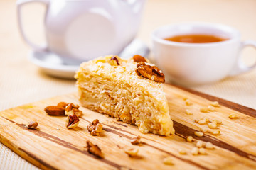 Napoleon cake with different nuts on wooden board