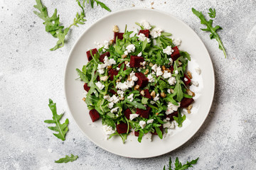 Fresh salad with arugula, feta cheese, walnut and beet on white plate. Beet salad