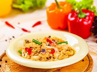 Pasta with seafood and vegetables in white plate on wooden cutting board