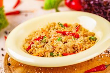 Rice with vegetables in white plate on wooden cutting board
