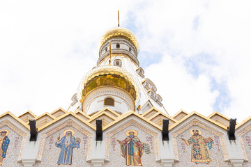 Bottom view of white church with gilt domes and images of saints