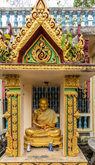 Ko Samui Island, Thailand - March 18, 2019: Wat Laem Suwannaram Chinese Buddhist Temple. Golden statue of sitting old monk in gold-green baldachin niche. Two vases in front. © Klodien