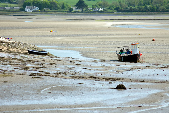 Wales &ndash; Anglesey island :  Low tide at Red Wharf bay.  Sand flats with stranded boats.  The green of the shoreline in the distance.