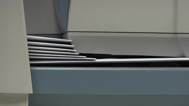 Franking machine pulling in a stack of enveloped letters one by one to apply postage - very close detail shot.