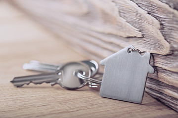 House key on house shaped keychain on wooden floorboards