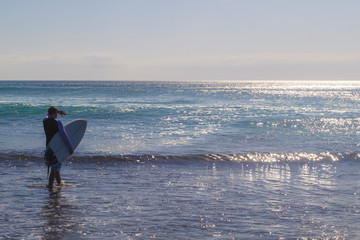 Male surfer entering the sea with his board.Ready for a great surfing day.