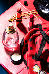 Elegant woman's hand on a perfume, red leather stool background. Sixties american style. Abstract conception.