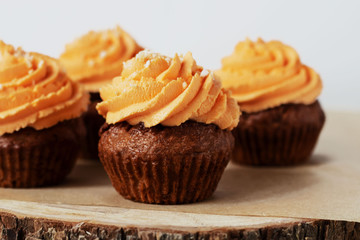 Fresh and tasty with orange frosting cupcakes on white background