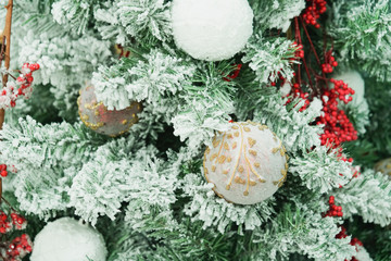 Snow-covered nice Christmas tree decorated with white balls and red baubles guarantee you perfect...