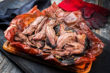 Traditional barbecue wagyu pulled beef in peach paper as closeup on a rustic board