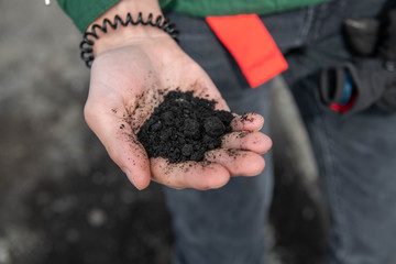 Hand Holding Black Volcanic Ash