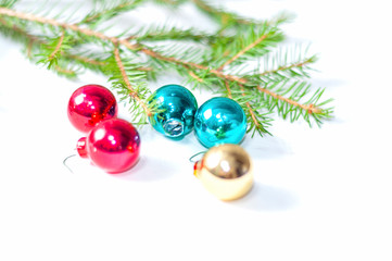 Multicolored small glass Christmas toys on spruce branches on a white background close-up. Christmas holiday background