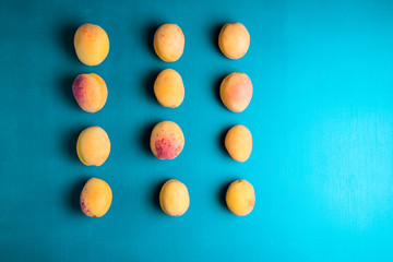 Many  apricots on a blue background. Flat lay composition with hard light