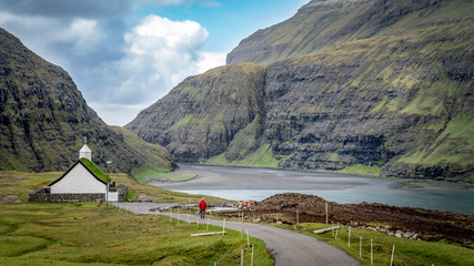 Unidentified man walking towards church from village of Saksun, Faroe Islands, Denmark