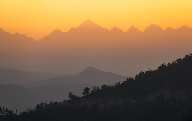 Fototapeta na wymiar The orange light of the morning sun hits the Panchachuli peaks in the Himalayan town of Munsyari in Uttarakhand.