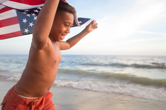 Patriotic fun at the beach young boy running with the American flag