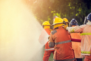 Firefighter spraying water to fire for heat protection, Team fireman training fighting fire.