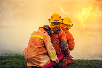 Firefighter spraying water to fire for heat protection, Team fireman training fighting fire.