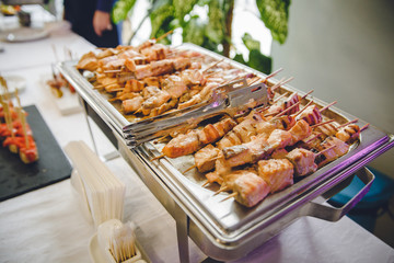 A lot of cooked fried roasted grilled meat or fish from a grill or oven lies on a metal tray. Photo for restaurant or stand-up meal or banquet. Delicious tasty food at the party.
