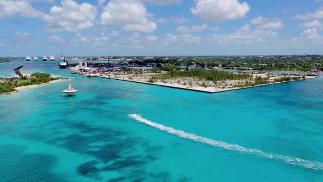 Aerial: Jet Skier Zooming Past Water Observation Tower Towards City of Nassau and Huge Cruise Ships