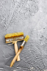 used construction brushes on a gray concrete background - obrazy, fototapety, plakaty