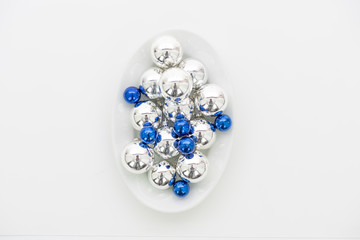 Blaue und silberne Weihnachtskugeln auf einem weißen Teller