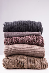 A stack of knitted winter sweaters on a white background.
