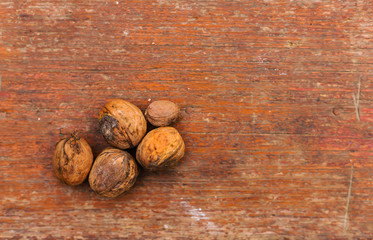 walnuts five pieces in a pile on an old scratched wooden background