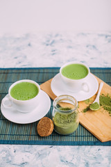  White cups with matcha and powder for its preparation.