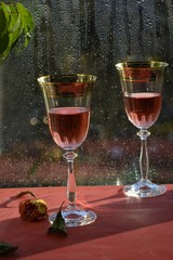 glasses with rose wine on the background of a window with raindrops
