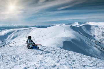 A snowboarder sits on a mountainside