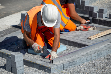 Construction workers laying paving bricks outdoor