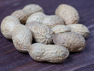 unpeeled peanuts on a wooden background