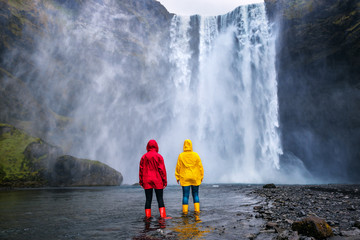 yelow and red friends watching on Skogafoss waterfall © Volodymyr Shevchuk