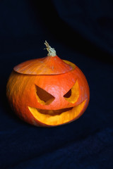 Carved scary pumpkin with dark background. Homemade Halloween decoration. Selective focus.