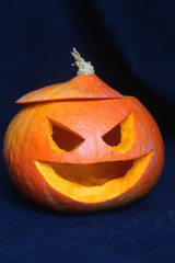 Carved scary pumpkin with dark background. Homemade Halloween decoration. Selective focus.