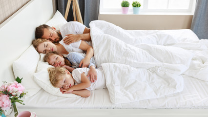 healthy sleep. happy family parents and children sleeping in white bed  .